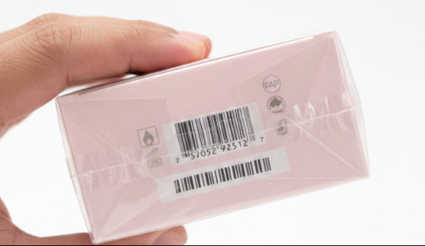 Bar-coded package held by a hand on a red background
