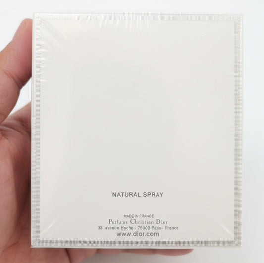 White Dior perfume box held by a hand on a red background
