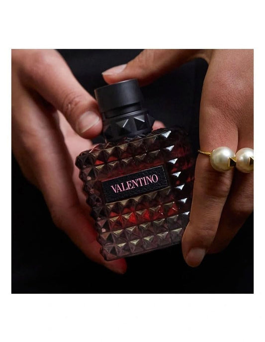 Valentino perfume bottle held by hands with a dark background