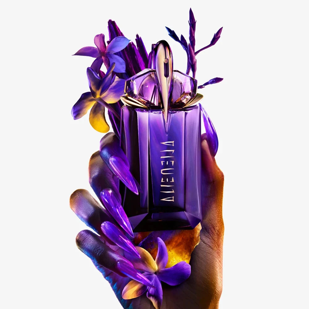 Viktor & Rolf Alien perfume bottle held by a hand with flowers on a white background