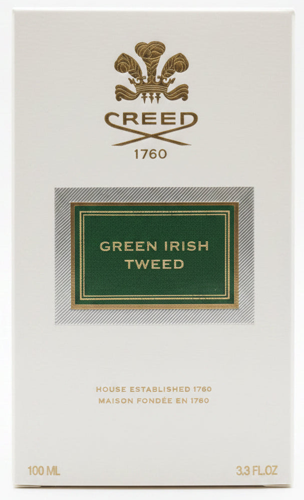 Creed Green Irish Tweed perfume box held by a hand on a red background