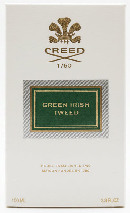 Creed Green Irish Tweed perfume box held by a hand on a red background