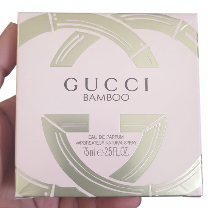 Gucci Bamboo perfume box held by a hand against a red background