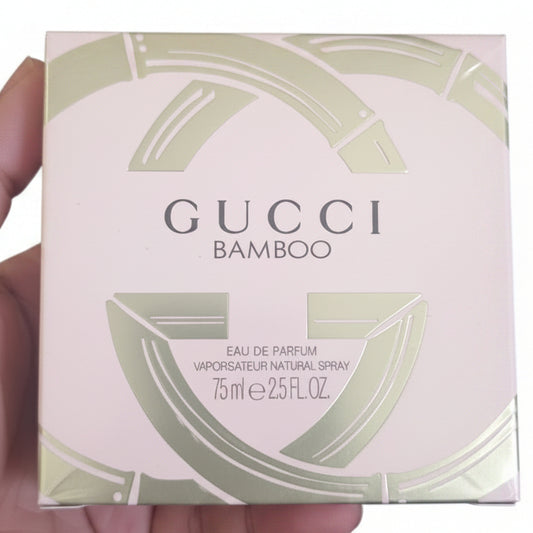 Gucci Bamboo perfume box held by a hand against a red background