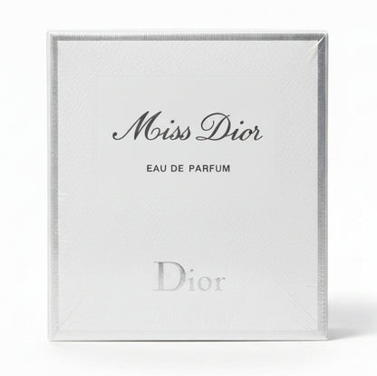 Miss Dior Eau de Parfum packaging held by a hand on a red background