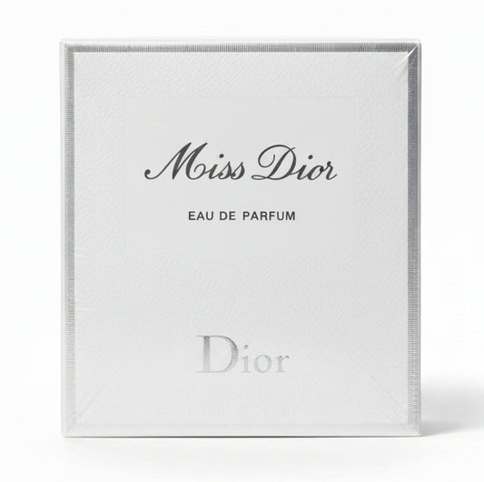 Miss Dior Eau de Parfum packaging held by a hand on a red background