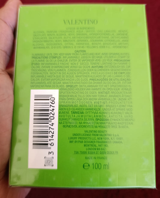 Green box with text and a barcode held by a hand against a red background