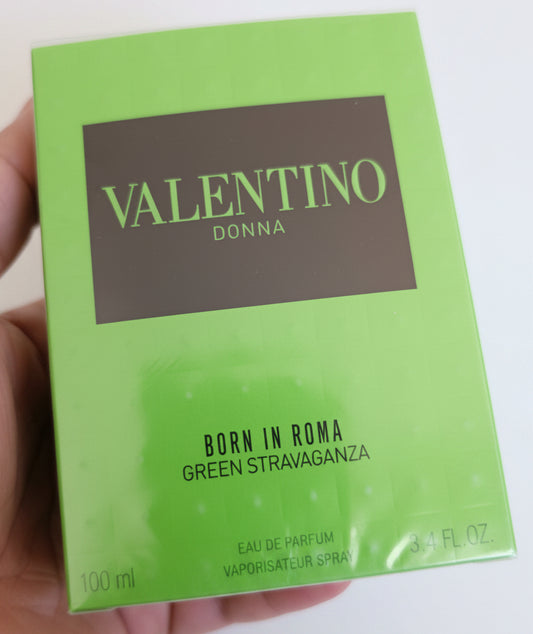 Valentino Donna perfume box held in a hand against a red background
