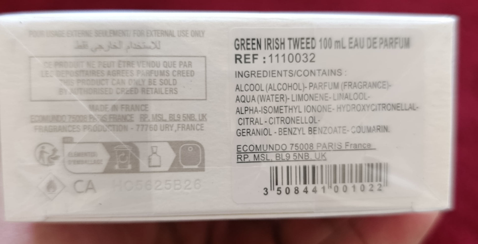 Product packaging held in a hand with a red background
